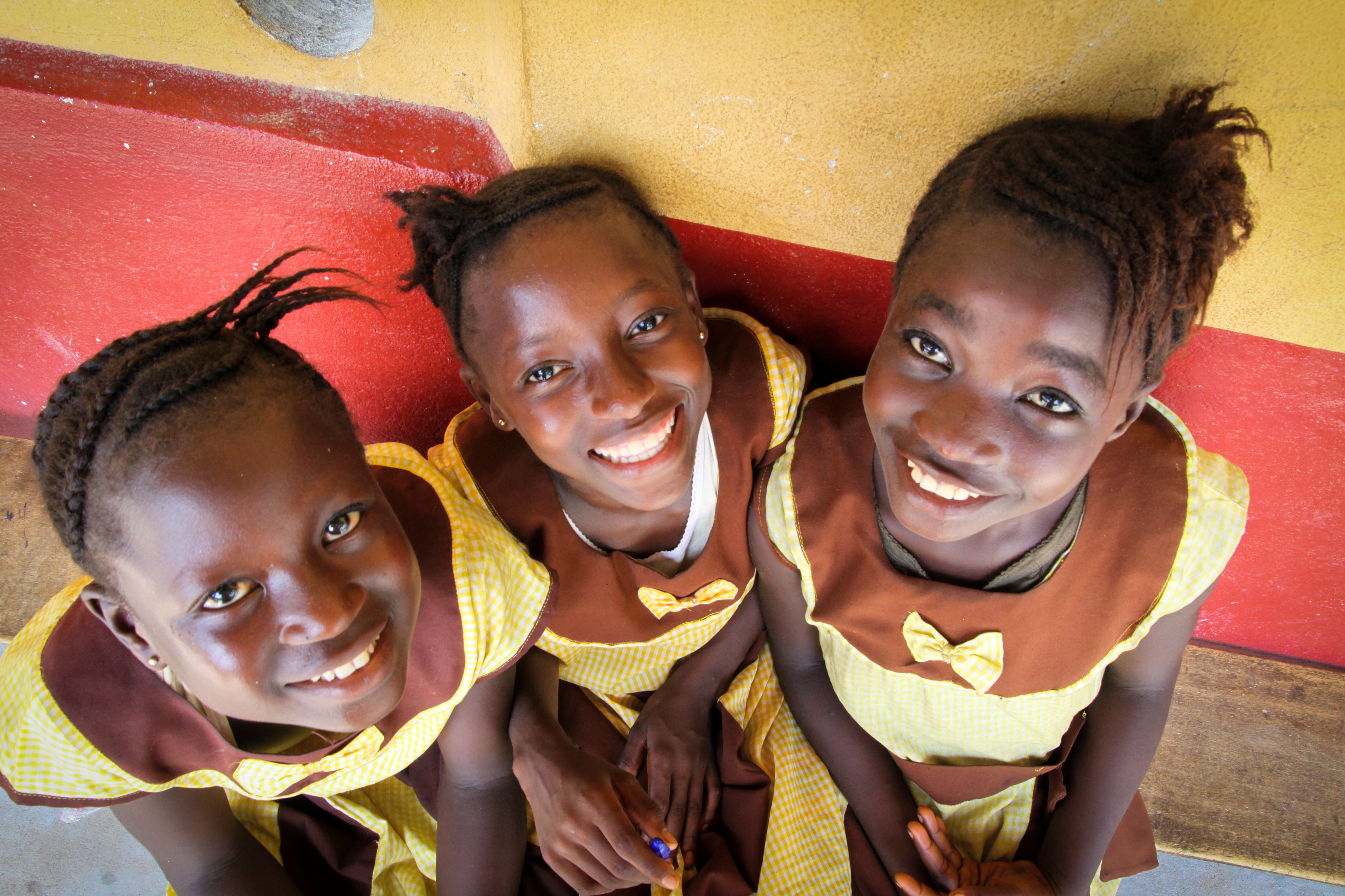 Drei Mädchen vor einer Volksschule in Sierra Leone.